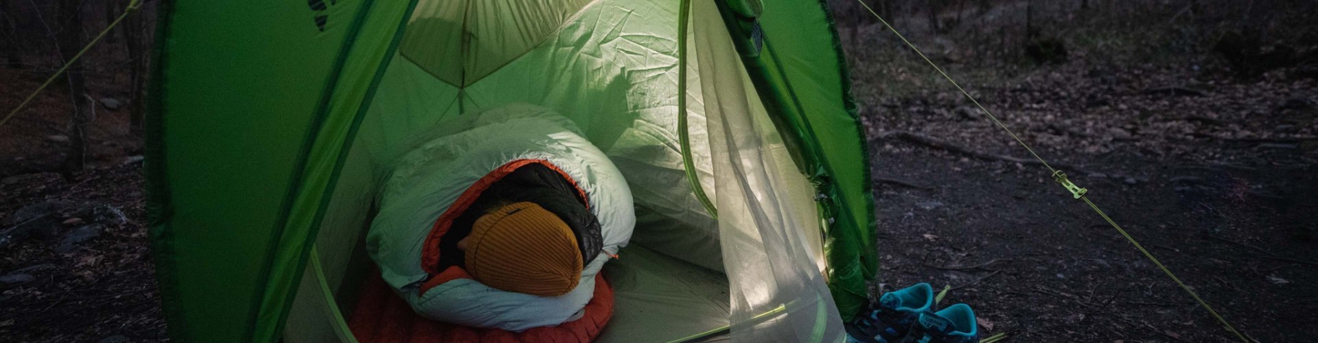 Svenja, de gestión de productos de bc, envuelta en su saco de dormir Deuter en una tienda de campaña de VAUDE.