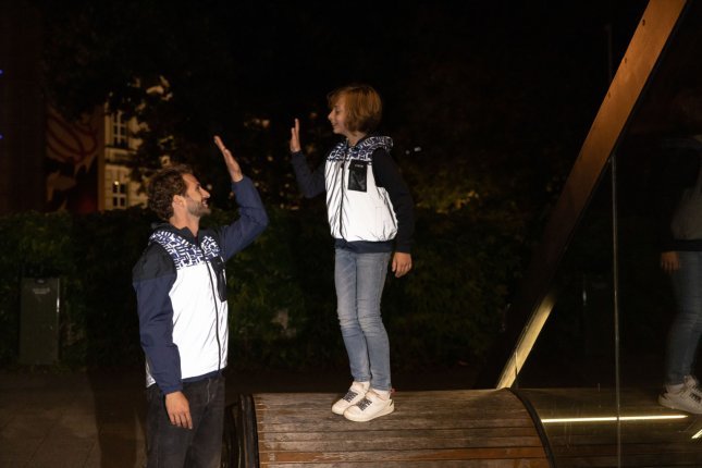 Ein Mann und ein ca. 10-jähriger Junge geben sich "High Five". Beide tragen grell in der Nacht reflektierende Westen