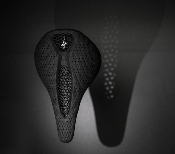 View of a black Specialized Power Mirror bike saddle from below against a dark background. The perforated design of the saddle is visible.