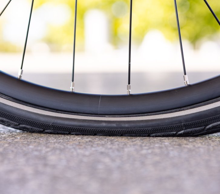 Close-up photo: A bicycle tyre with too little air is heavily compressed. The contact patch looks enormous.