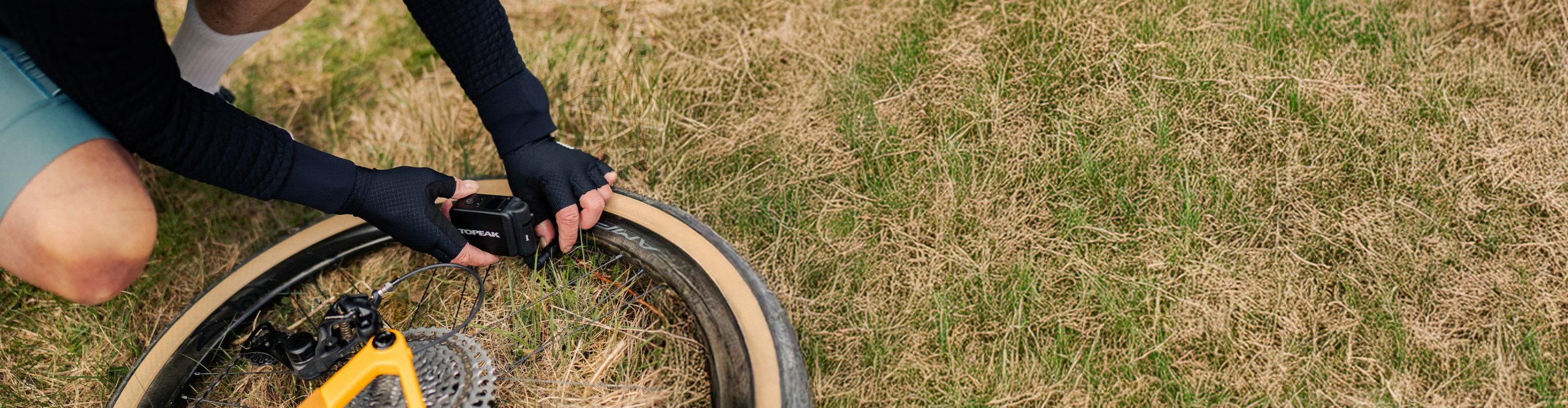 Radfahrer repariert Fahrradreifen mit einer Topeak Minipumpe unterwegs – schnelles Aufpumpen bei Panne auf Gravel- oder Rennradtour.