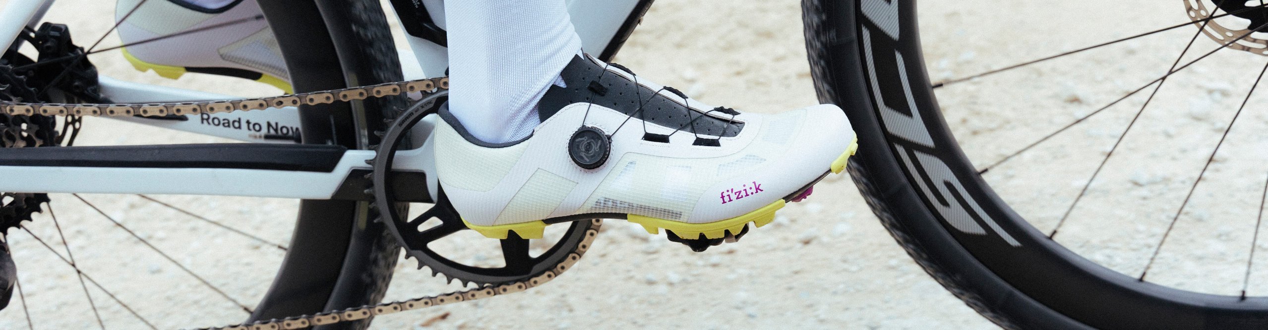 Zapatilla de ciclismo gravel Fizik Vento Proxy blanca con cierre BOA sobre el pedal de una bicicleta gravel