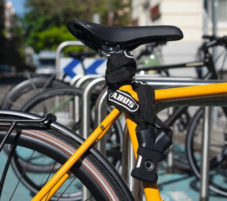 Bicicleta asegurada con un candado ABUS YARDO a un soporte; el candado se abre mediante sensor de huella dactilar.