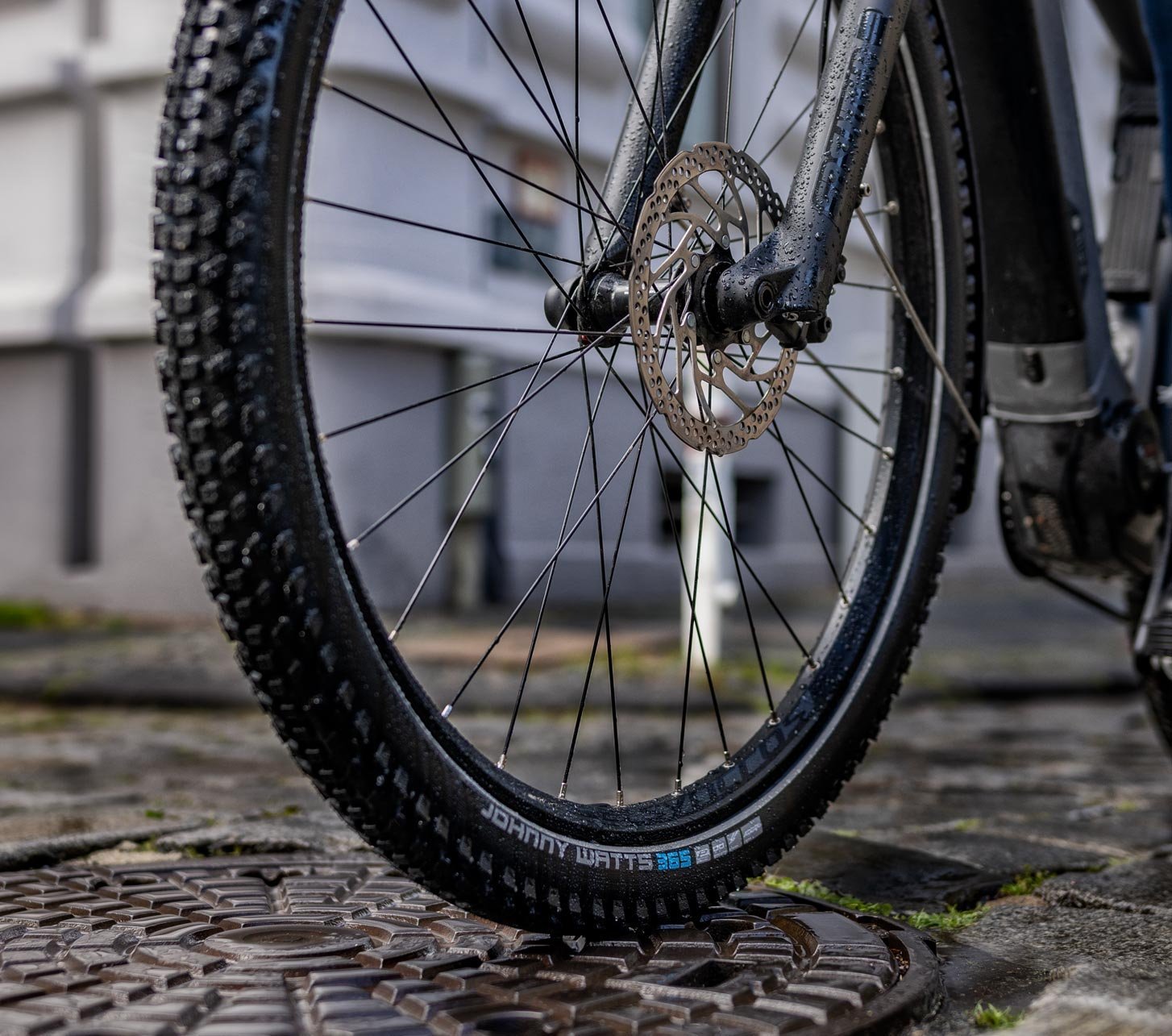 Gros plan du pneu Schwalbe Johnny Watts 365 pour vélo électrique sur pavés mouillés – pneu polyvalent toutes saisons pour e-bike urbain avec adhérence et protection anti-crevaison
