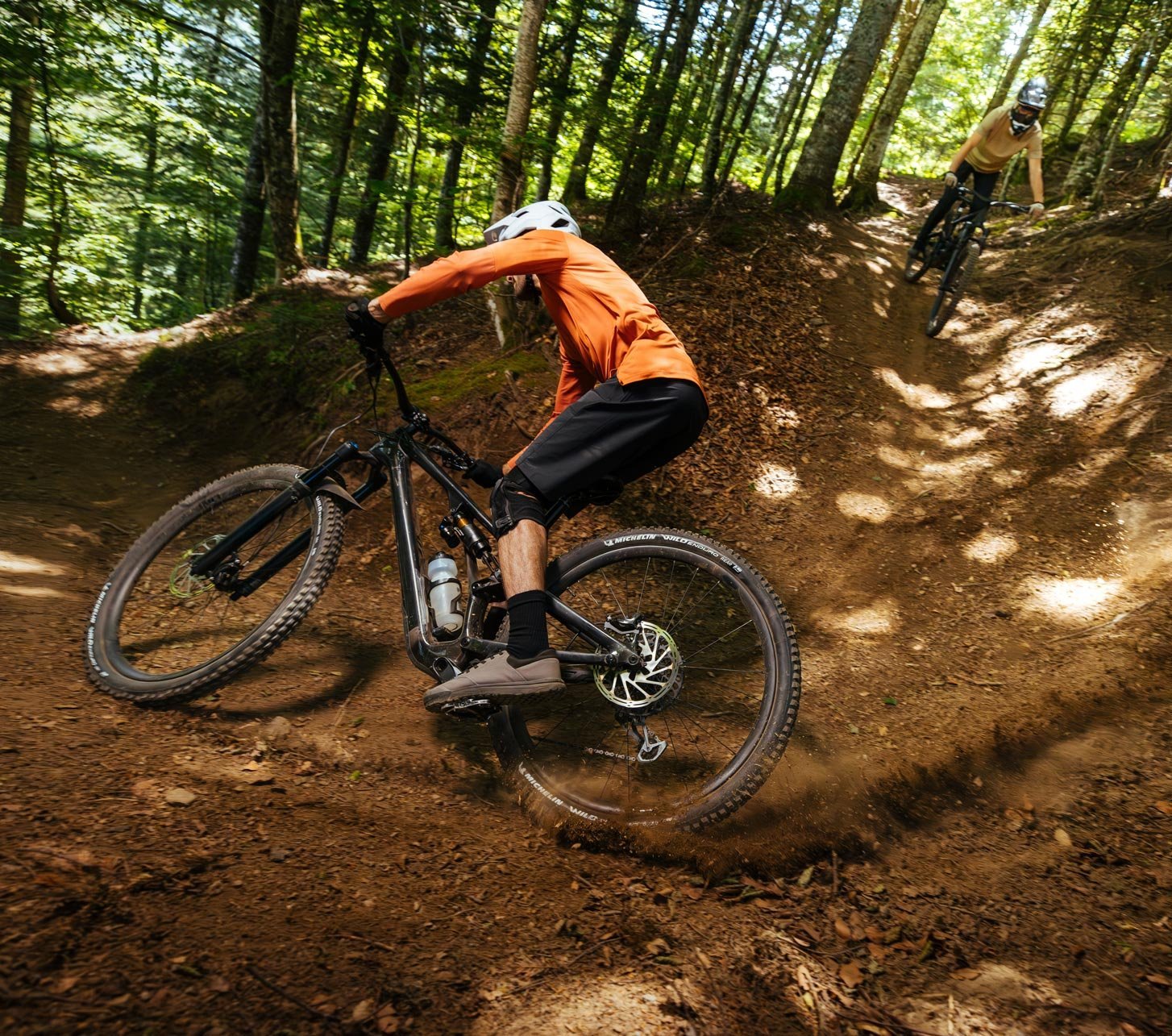 Michelin Wild Enduro Performance tires on a mountain bike riding a dusty forest enduro trail with strong grip, control and off-road traction