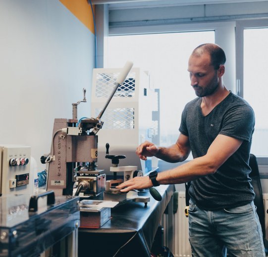 Pictured is a testing machine for bag materials. It is operated by an employee.