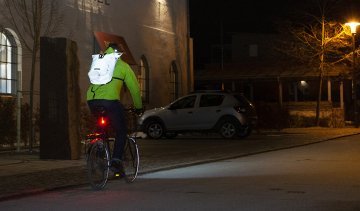 Fahrradfahrer mit reflektierendem Rucksack im Straßenverkehr