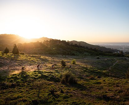 4 Mountainbiker im Sonnenuntergang auf Trail