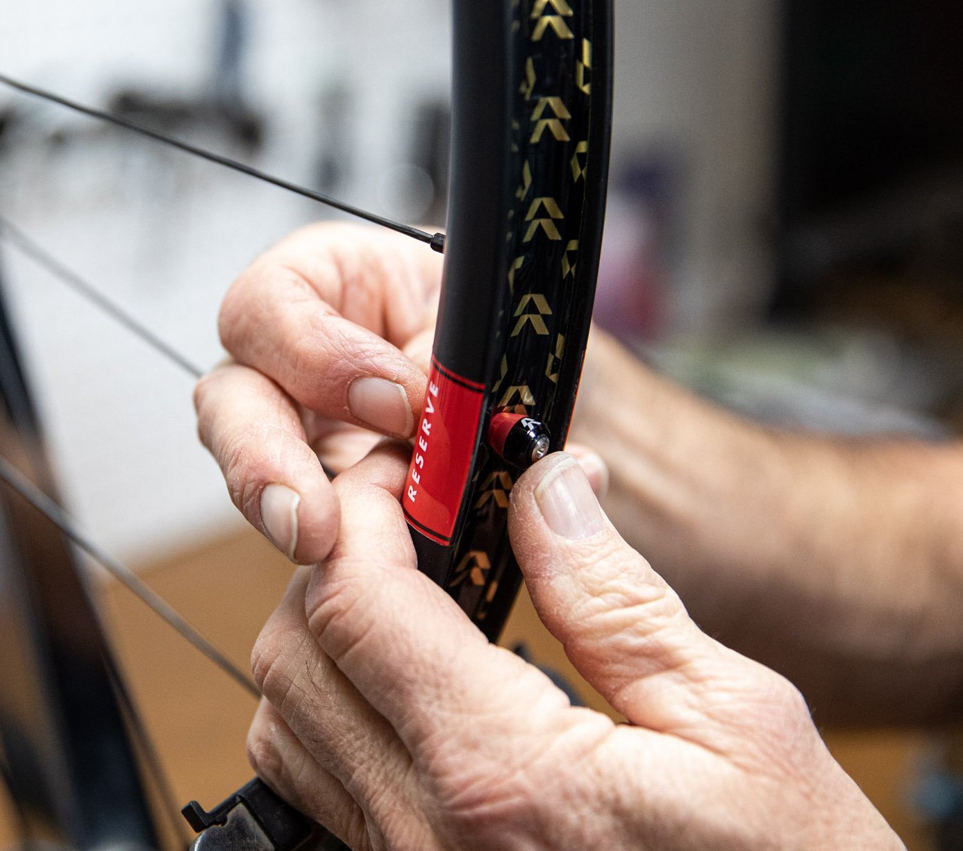 Close-up: hands applying tubeless rim tape to a Reserve bicycle wheel rim.