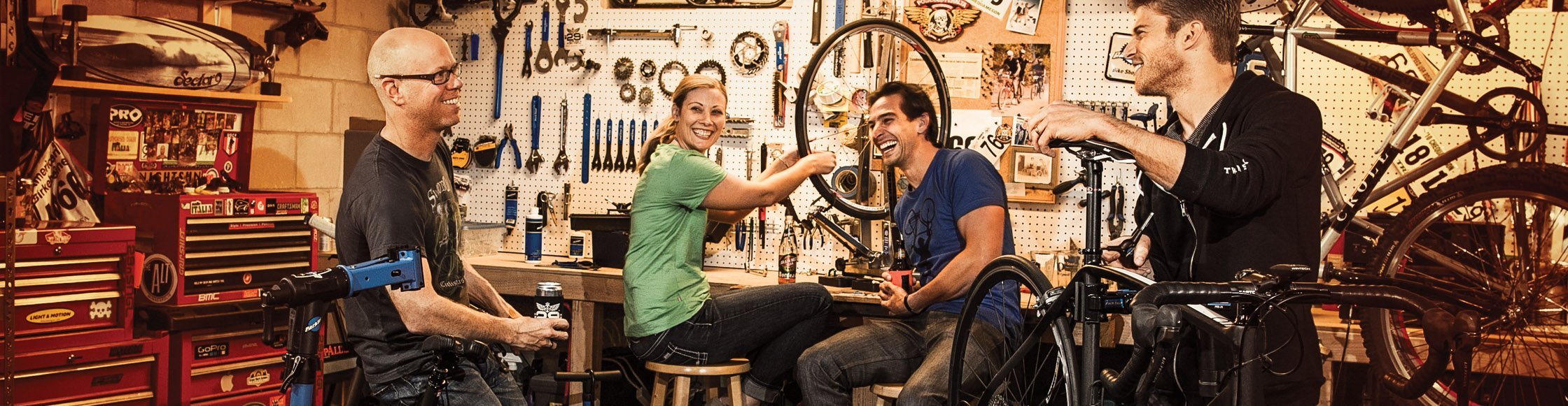 ParkTool Fahrrad Werkzeug in einer Fahrradwerkstatt, 3 Männer und eine Frau schrauben fröhlich an Fahrrädern