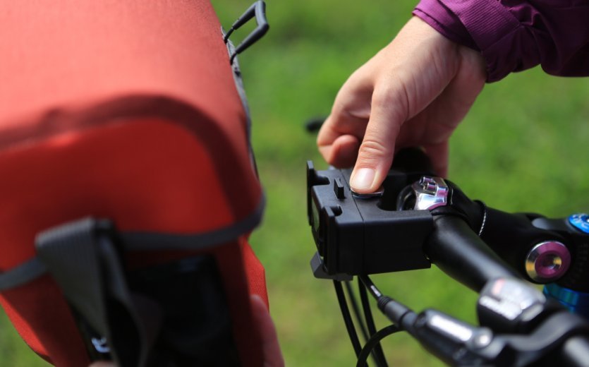 A hand removes the Ortlieb bicycle bag from the handlebar.