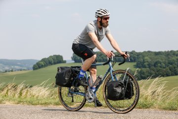 Junger Mann auf einer Radreise mit Gepäcktaschen und Lowrider