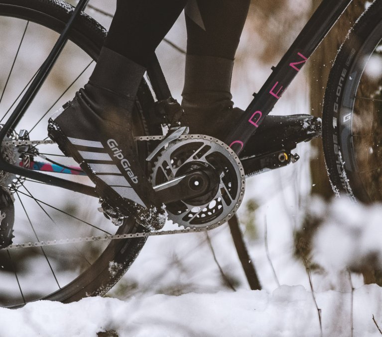 Detalle de pies pedaleando una bicicleta en un paisaje nevado.
