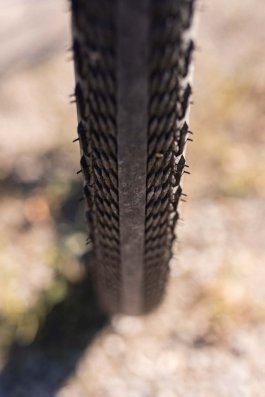 Vue frontale d’un pneu gravel semi-slick avec bande centrale lisse et crampons latéraux pour plus d’adhérence.