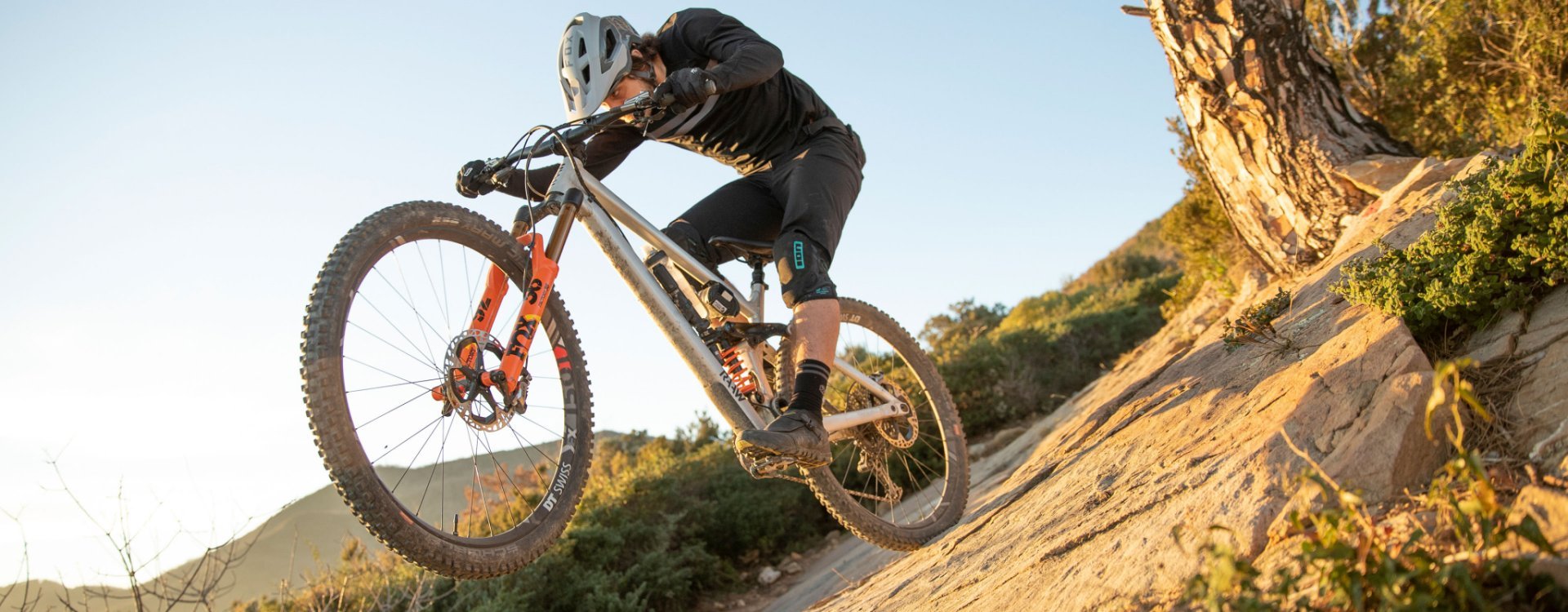 Christian from bc Product Management rides on the rear wheel of his RAAW bike over rocky ground.