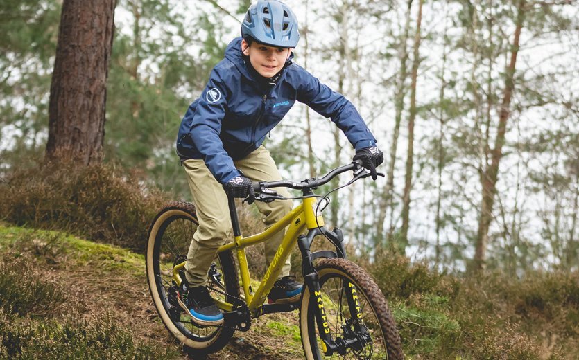 Ein Kind fährt mit dem SUPURB BO24 einen Trail im Wald