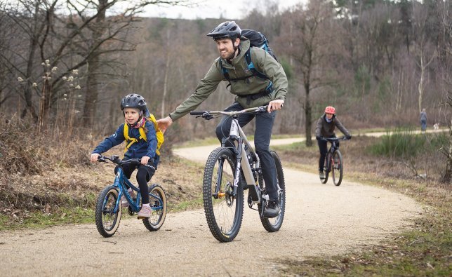 Un enfant et un adulte font du cyclisme tout-terrain. Ils sont en route sur un chemin de gravier.