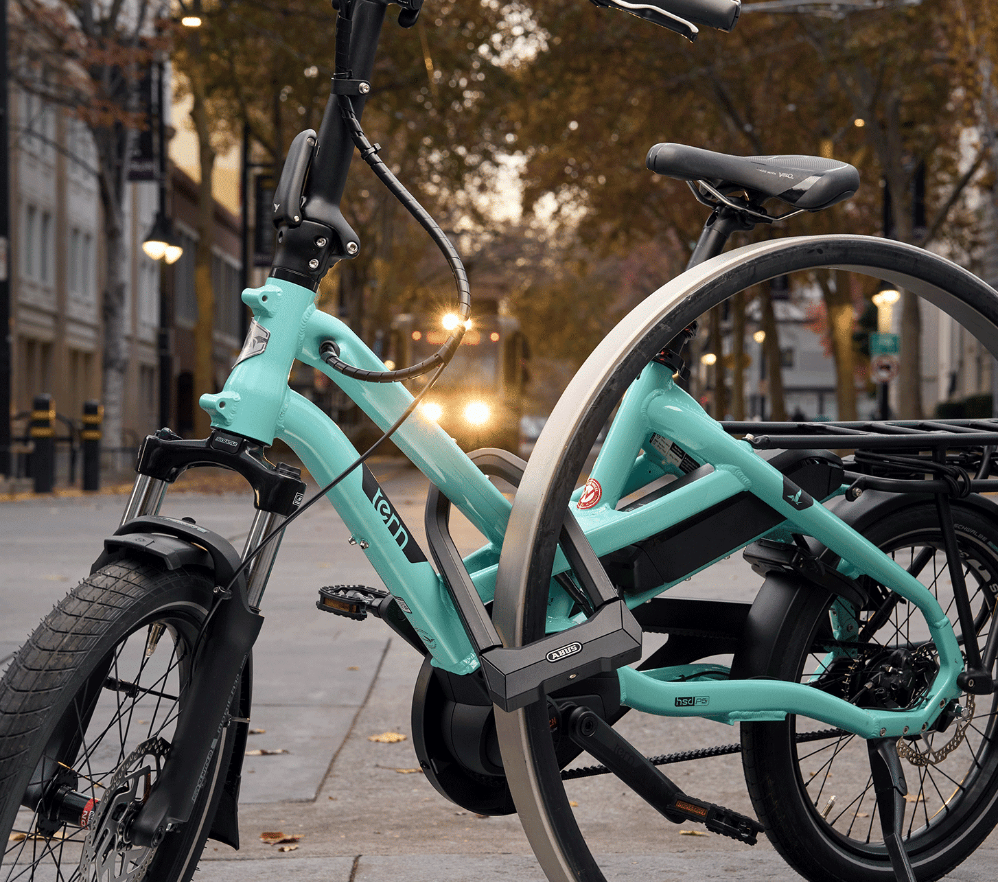 Turquoise Tern electric cargo bike secured to an urban bike rack with an ABUS U-lock.
