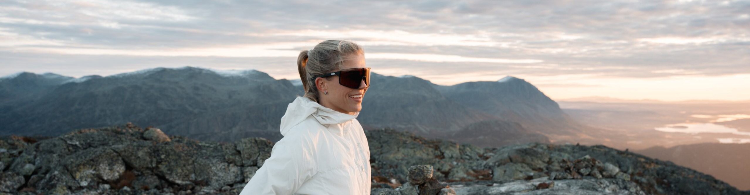 Sportlerin auf Gipfel vor Bergpanorama mit bliz Sportbrille bei Sonnenaufgang