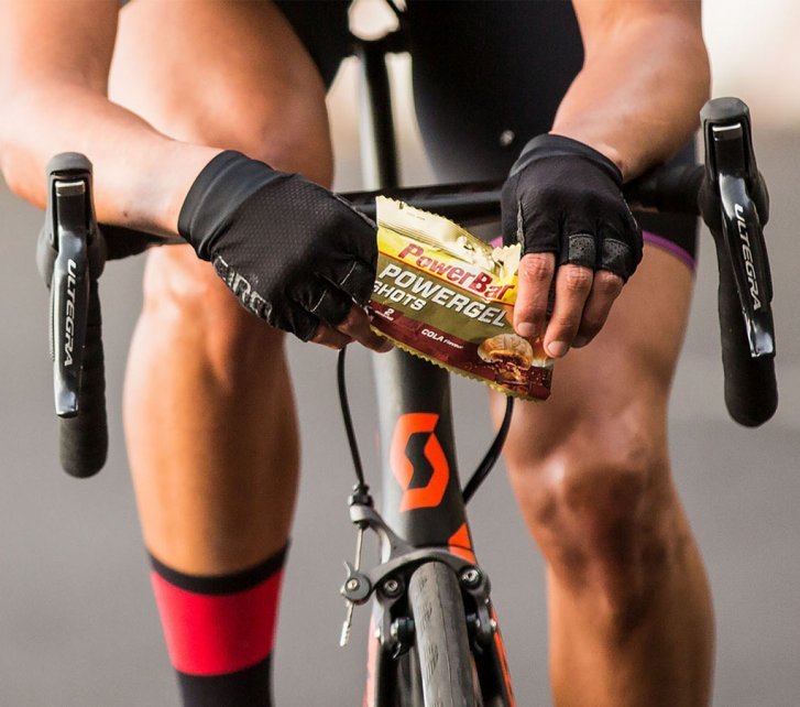 A biker opens a bag of fruit gummies while riding.