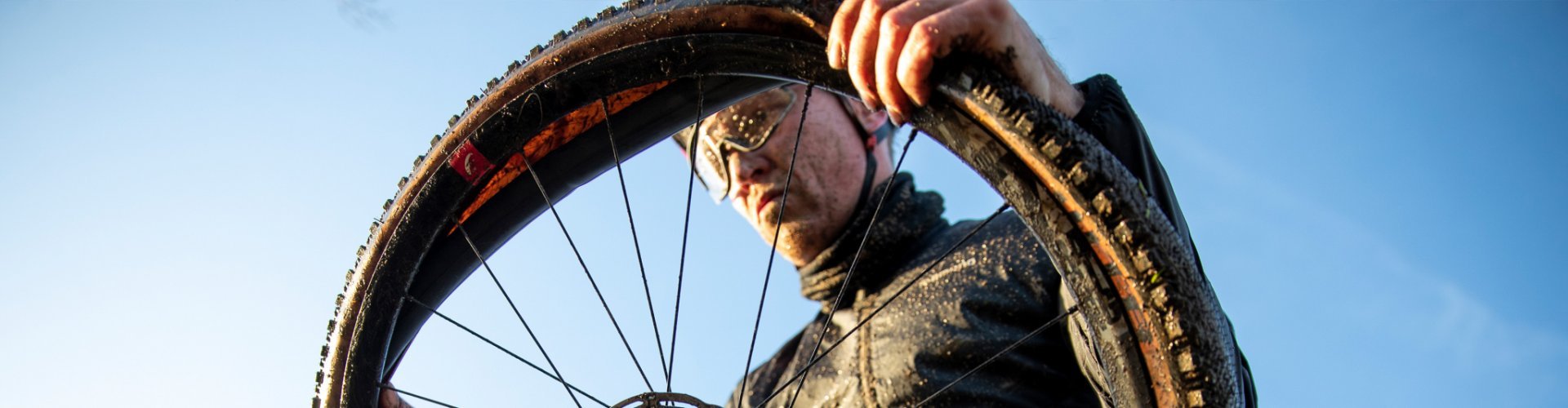 Ein Biker montiert nach einer Panne einen neuen Schlauch zwischen Felge und Reifen seines Gravelbikes.