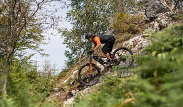 Christian from bc Product Management rides downhill on rocky ground on a Santa Cruz full-suspension mountain bike.