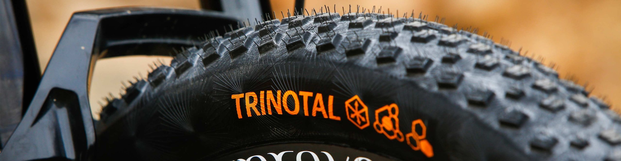 Nahaufnahme eines Continental Trinotal Mountainbike-Reifens mit grobem Profil an einem Fahrrad im Gelände