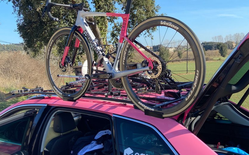 La imagen muestra una Cannondale SuperSix EVO con los colores distintivos de EF Education Easy-Post en el portabicicletas de un vehículo del equipo. 