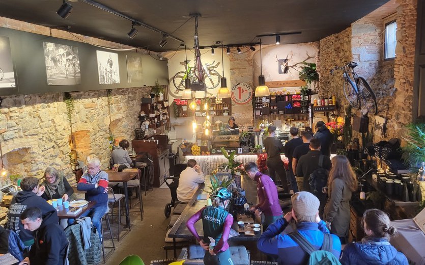 The interior of a busy café in Girona. Bikes and pictures from the cycling world hang on the walls. 