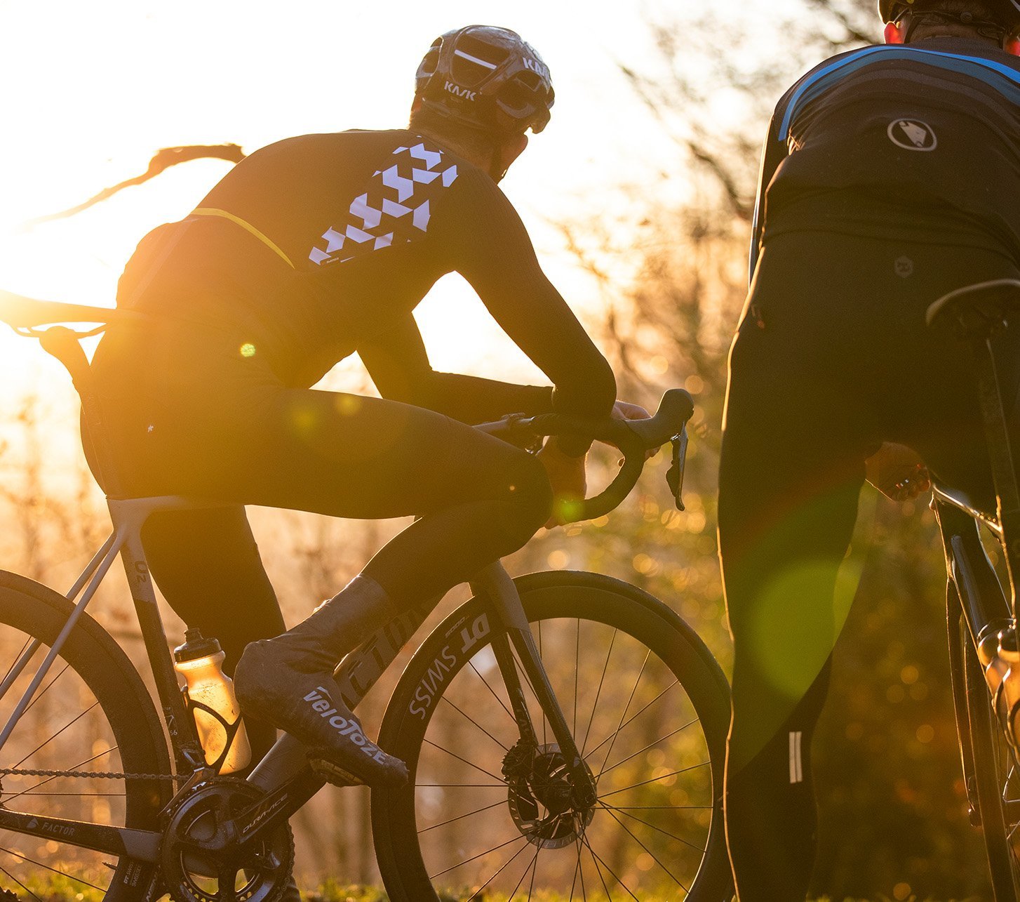 Zwei Rennradfahrrer mit DT Swiss Laufrädern stehen nebeneinander und betrachten den herbstlichen Sonnenuntergang.