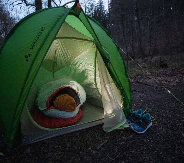 Svenja, de gestión de productos de bc, envuelta en su saco de dormir Deuter en una tienda de campaña de VAUDE.