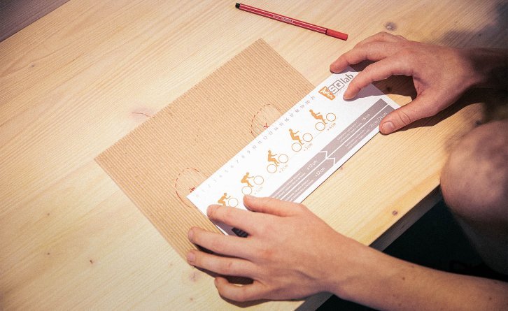 The distance between the two imprints on the corrugated cardboard is being measured with a measuring gauge.