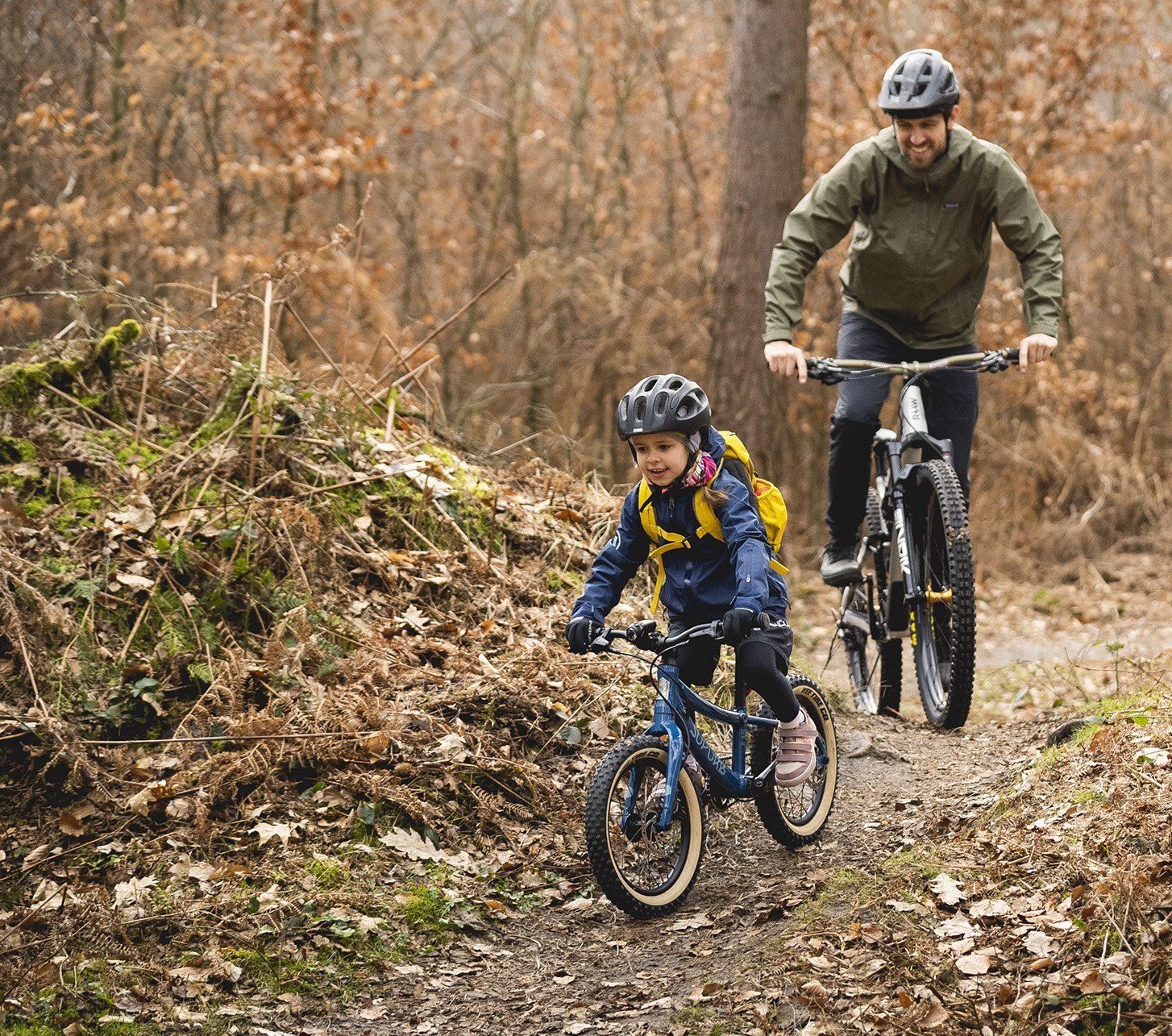 Ein Kind fährt seinem Vater mit einem SUPURB Kinderfahrrad voraus.