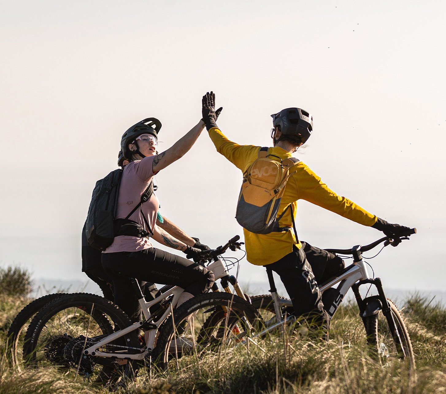 Mountainbiker mit evoc Rucksäcken geben sich Highfives