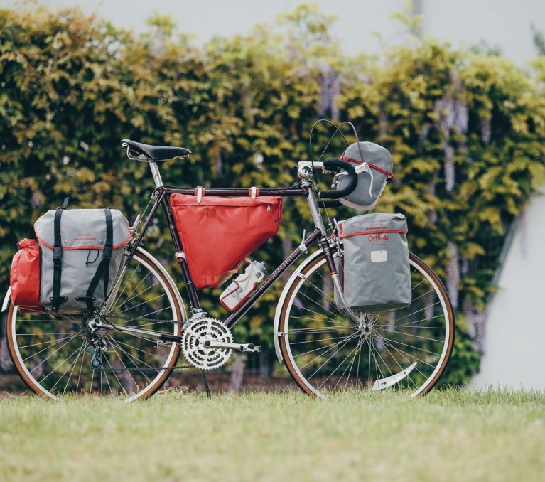 La photo montre un vélo de route en acier qui est équipé de diverses sacoches pour le bikepacking d'Ortlieb.