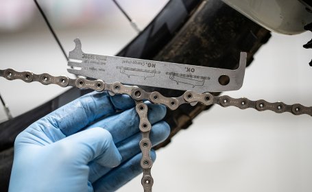 A close-up of a chain wear indicator holding the ends of a taut chain. 