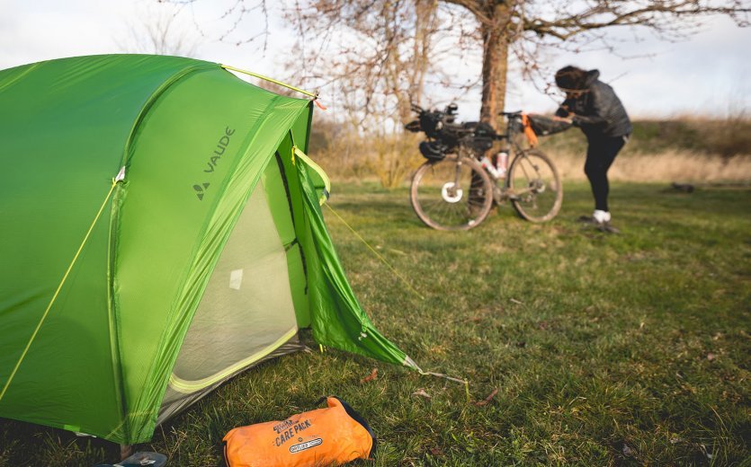 Christian from the bc Service Team packs his saddle bag. In the foreground is his tent, next to it is a stuff sack from Ortlieb.