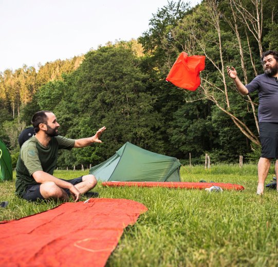Christian from the bc Service Team packs up his camping mat. In the foreground is his tent, in the background is his bicycle.