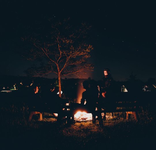 Die vier Gravelbiker sitzen in der Nacht entspannt an einem Lagerfeuer.