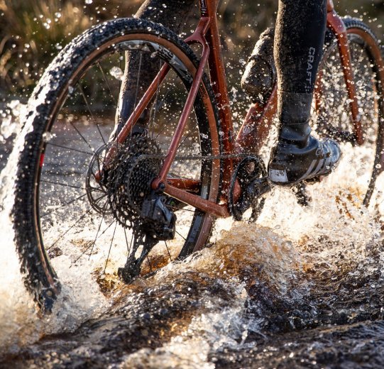 Ein Biker fährt durch eine große Pfütze.