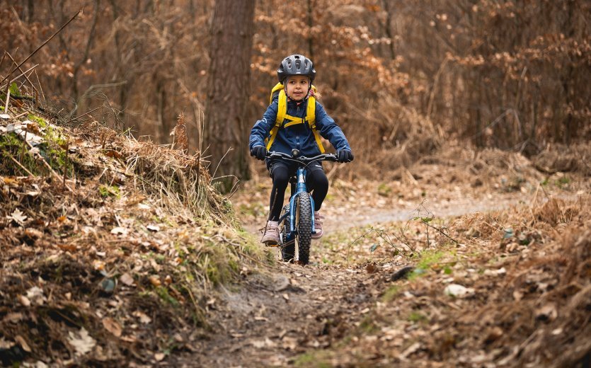 Ein Kind fährt mit dem SUPURB BO16 einen Trail im Wald
