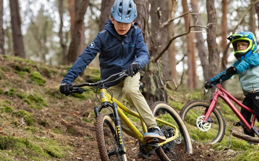 Ein Kind fährt mit dem SUPURB BO24 einen Trail im Wald