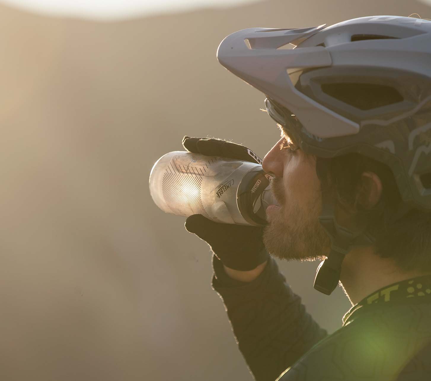 Mountainbiker trinkt aus seiner Trinkflasche vor Bergpanorama