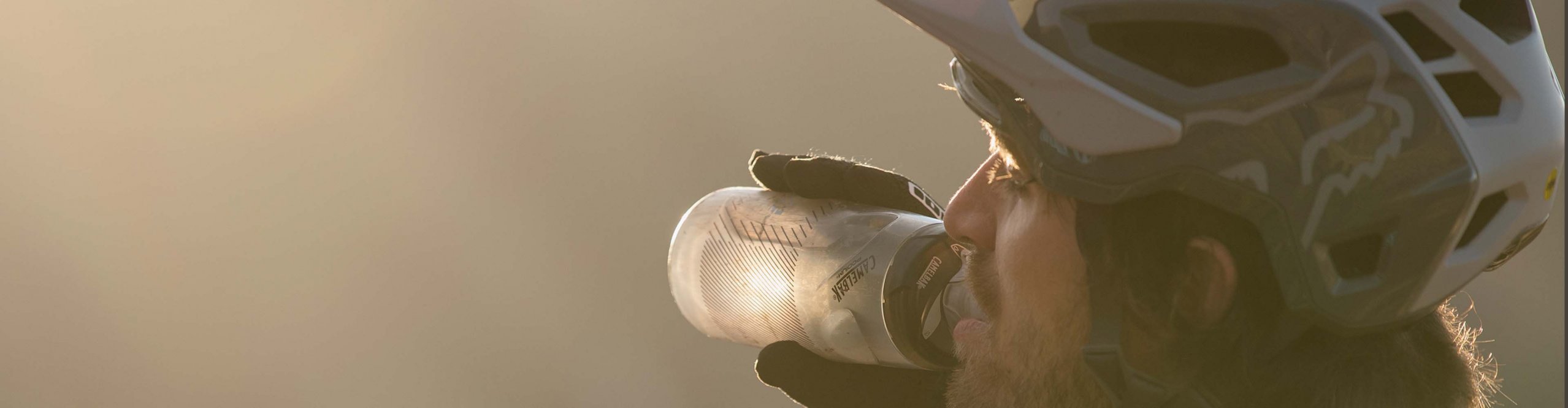 Mountainbiker trinkt aus seiner Trinkflasche vor Bergpanorama