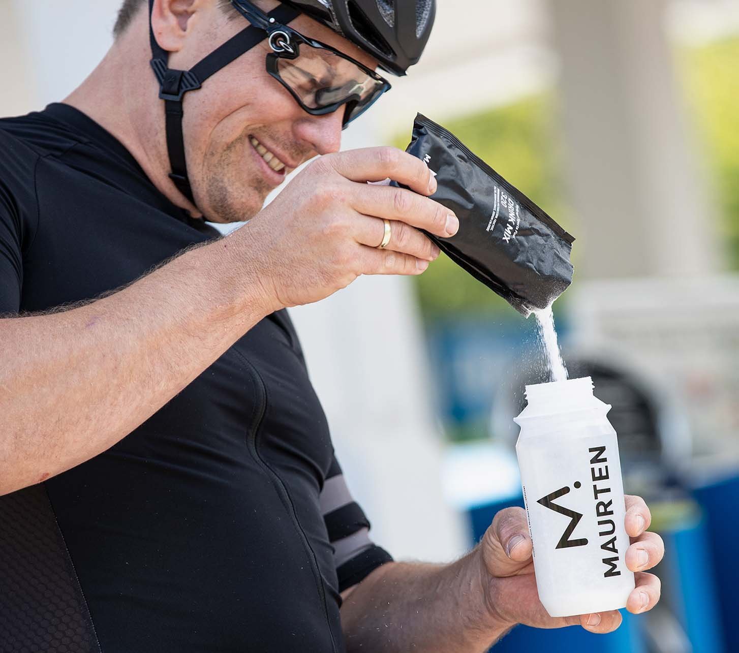 Radfahrer füllt seine Trinkflasche mit Elektrolytpulver auf.
