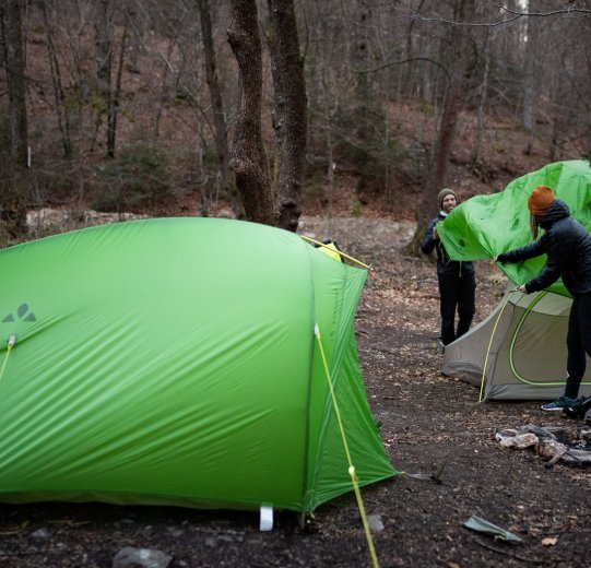 Rainer und Svenja von bc bauen ein Zelt auf. Im Vordergrund steht ein bereits aufgerichtetes Zelt von VAUDE.