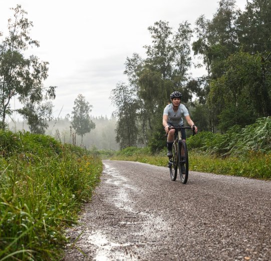 Un ciclista de Gravel montando por un camino de gravilla.