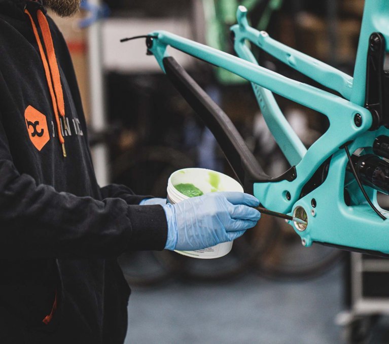 Ein Mechaniker fettet das Tretlagergehäuse eines Santa Cruz Mountainbikes.