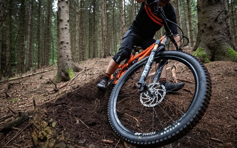 Christian fait un drift avec son VTT YETI sur un terrain boisé.