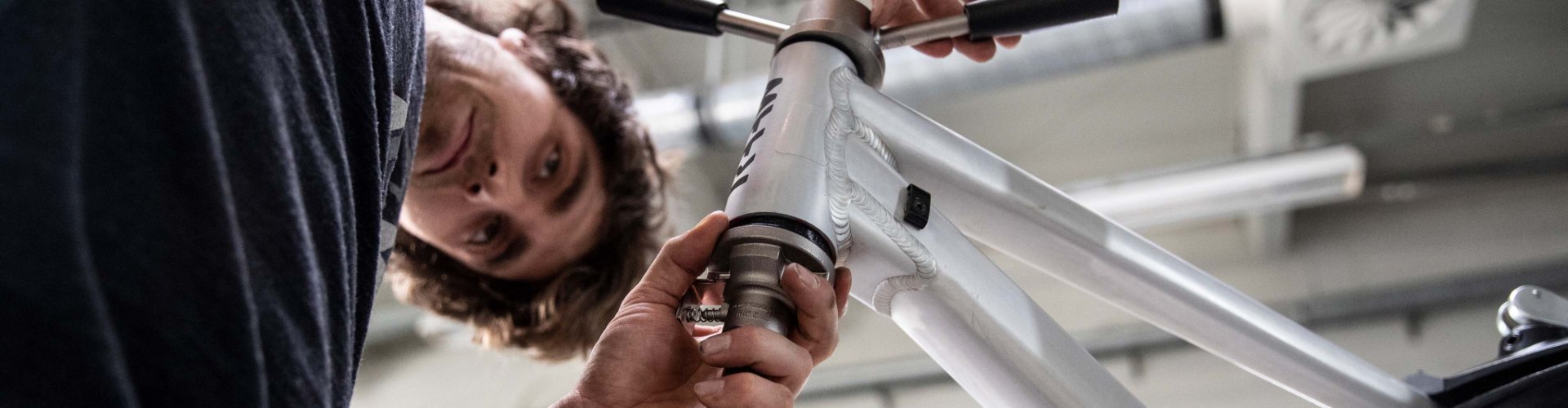 A mechanic presses the bearing cups of his Zero Stack headset into a RAAW Madonna frame.